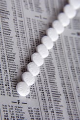 Row of aspirin on page of daily stock report